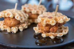 Syrup pools beneath mini chicken and waffle sliders
