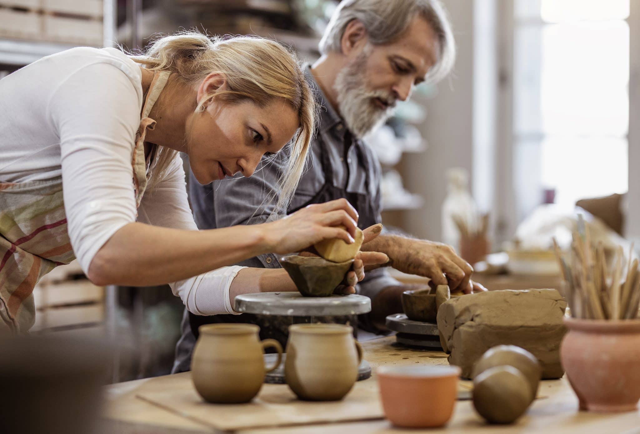 A man and woman learn pottery basics, one of the many fun hobbies you can explore from your home at Shoal Creek.