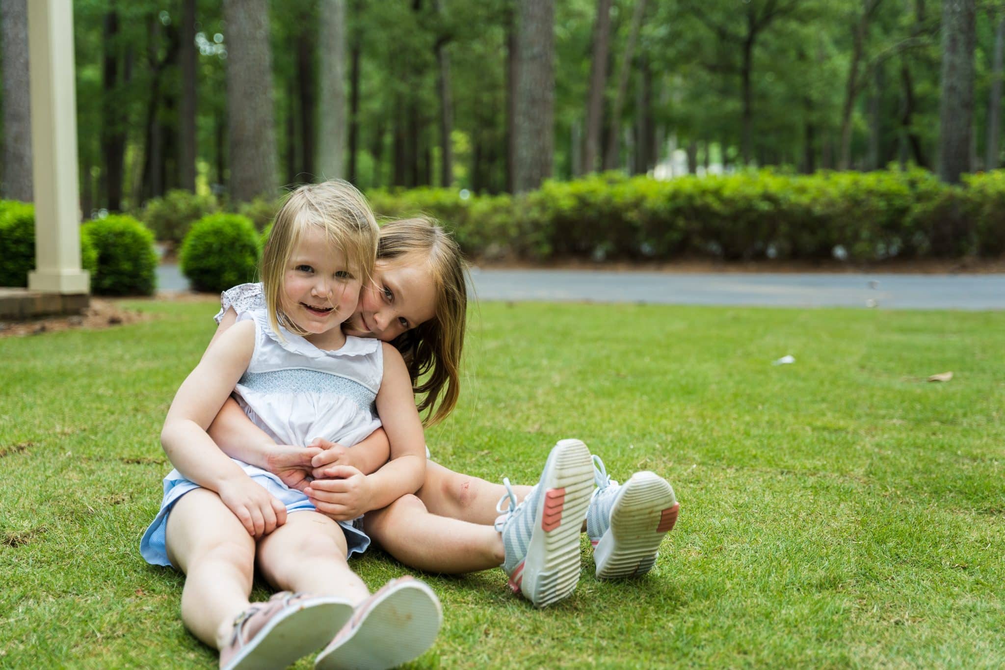 Two young girls sitting on the lawn of their Shoal Creek home, where they have access to the best schools in Birmingham.