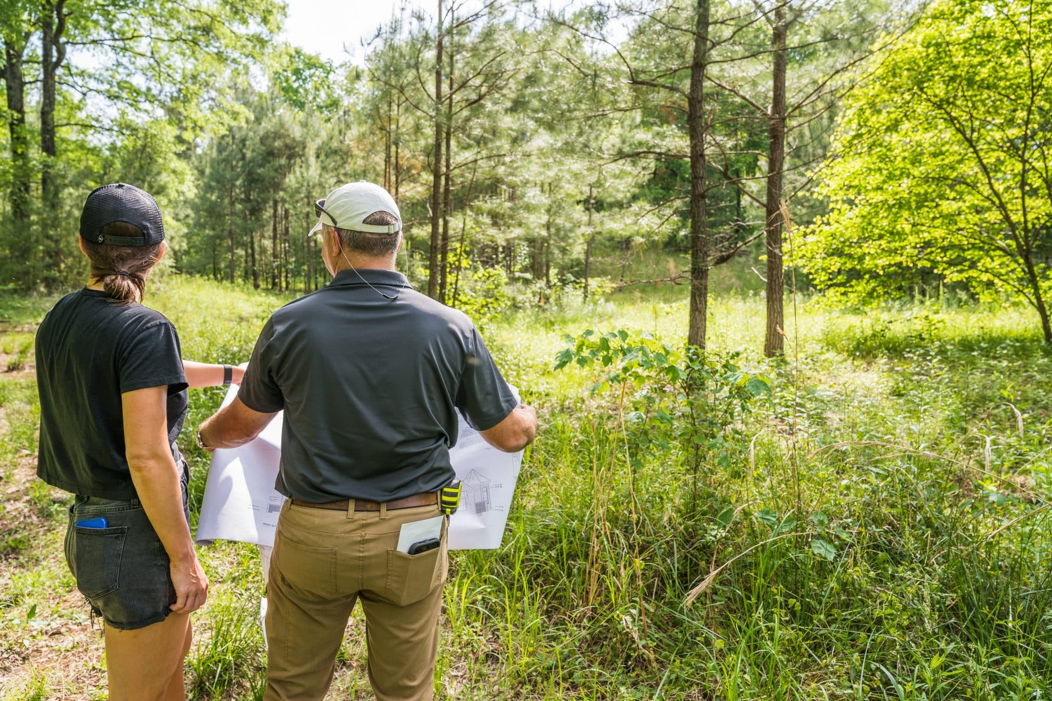 A project manager and Shoal Creek resident look at custom home blueprints on a fresh plot of beautiful land