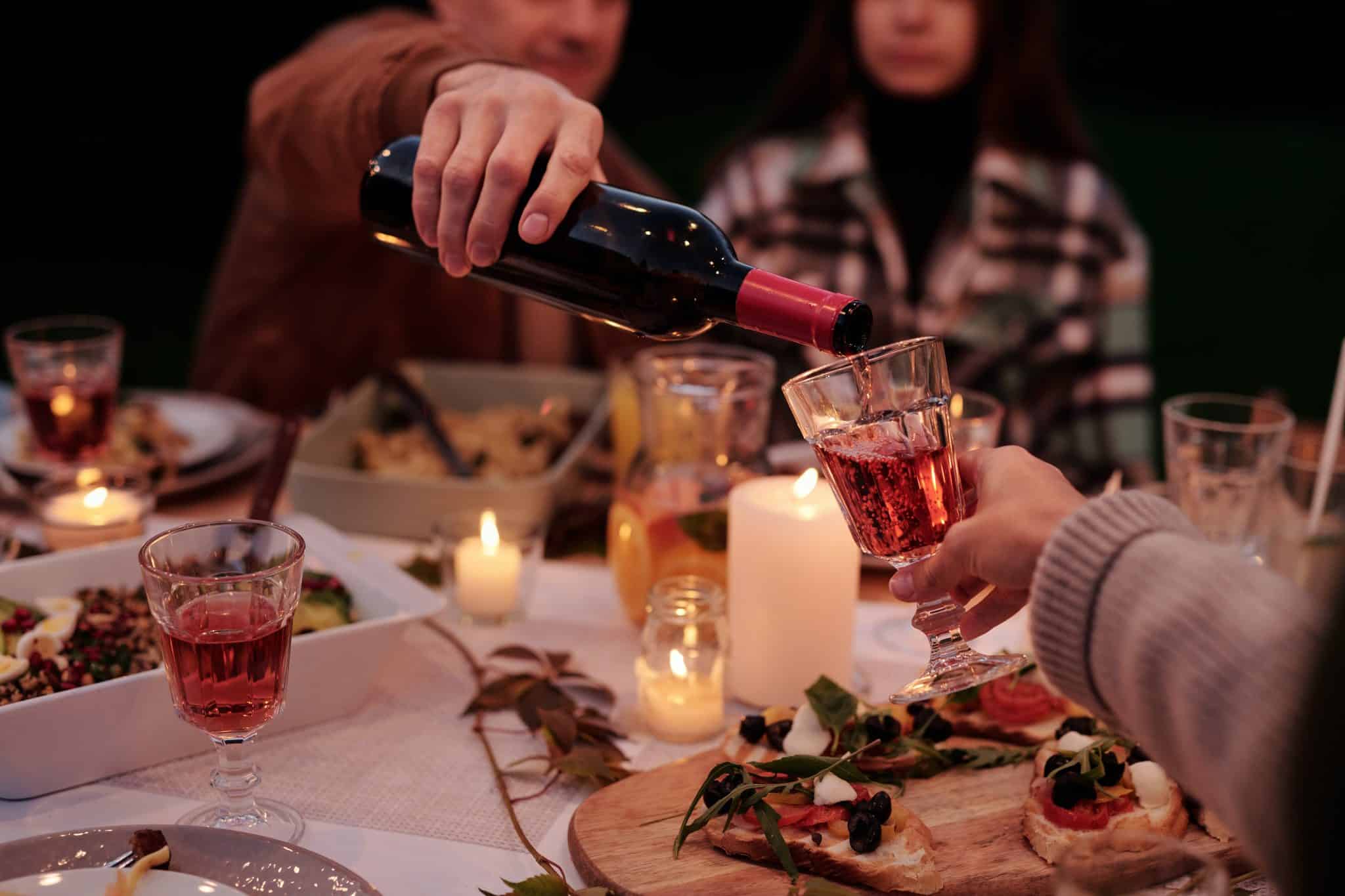 Residents hosting Thanksgiving, pouring wine in the foreground over a festive table