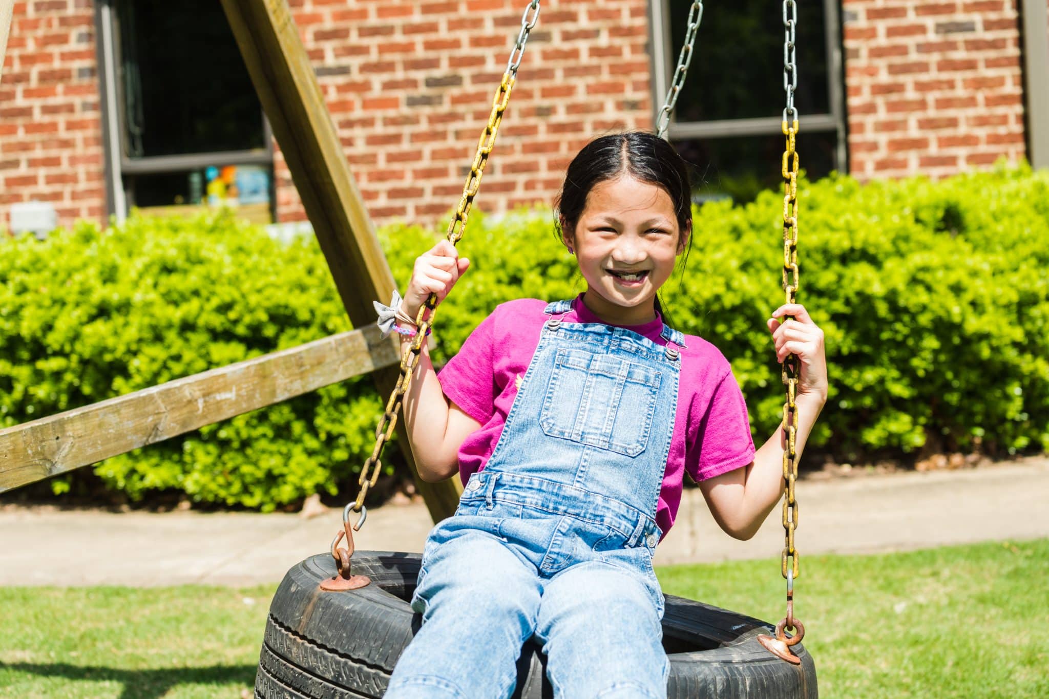 A young girl sitting on a tire swing in her backyard in Shoal Creek