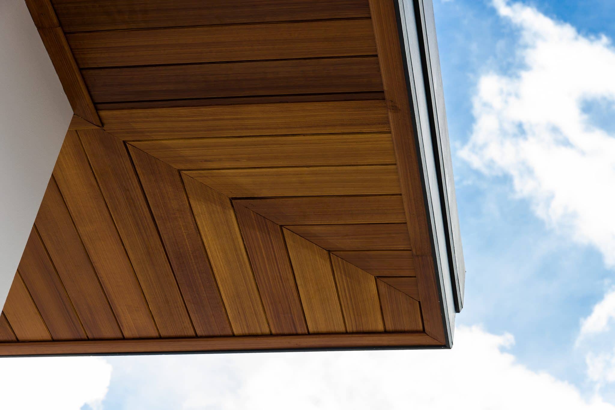 Underside view of a luxury home’s soffit, which uses natural building materials, with blue sky behind