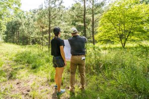 Two people survey land for sale in Birmingham and review a sheet of architectural plans