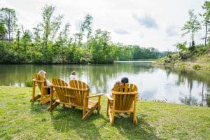 A Shoal Creek family relaxes in adirondack chairs facing the lake