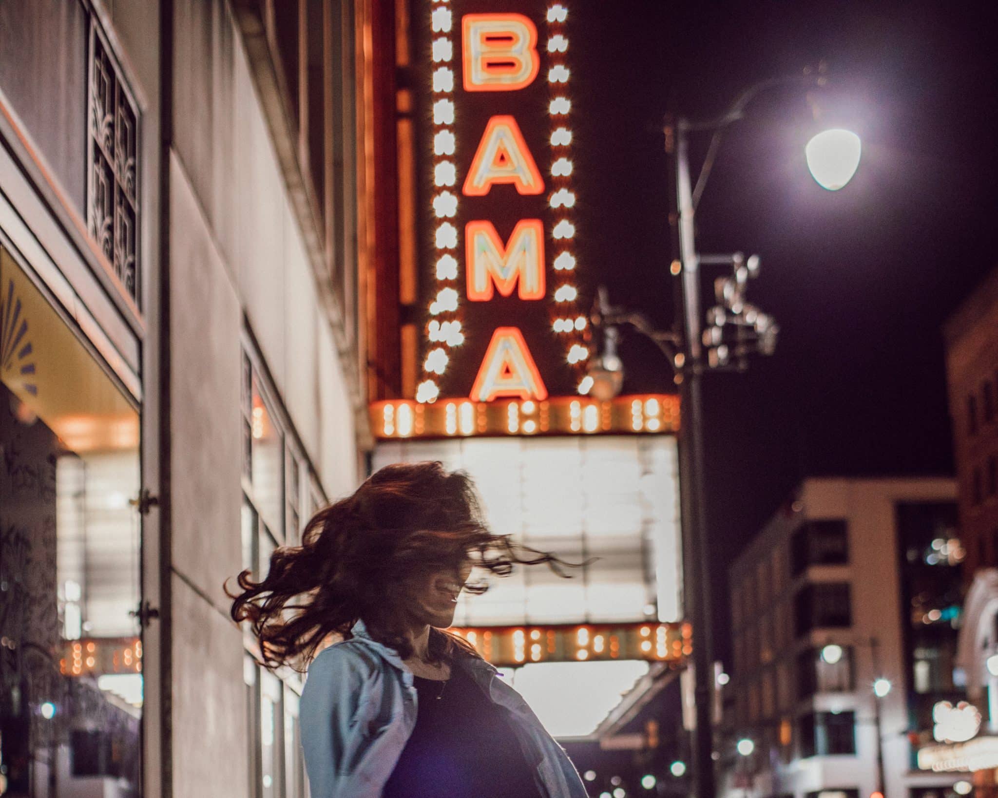 A woman spins in front of the Alabama Theatre, one of many things to do in Birmingham Alabama.