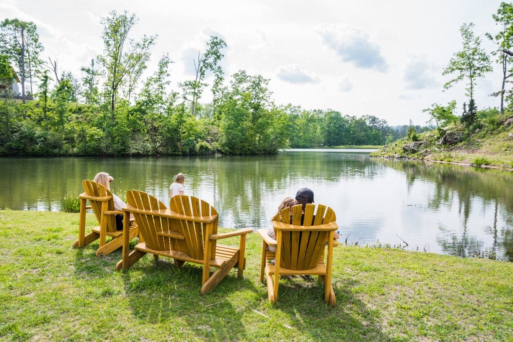 Shoal Creek residents sit in outdoor chairs enjoying the lakefront view from their property