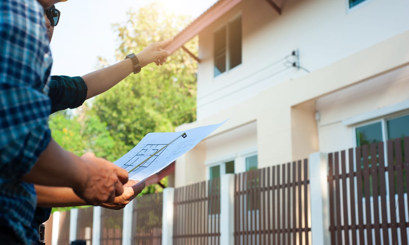 A homeowner goes over questions to ask builders when building a new home in front of a custom home