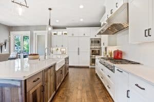 A custom kitchen with tall white cabinets and an island with built-in sink