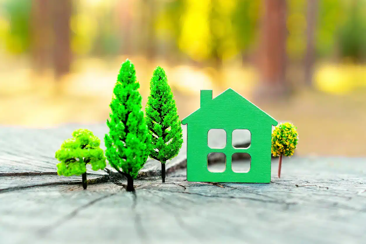 A tiny green house surrounded by tiny trees.