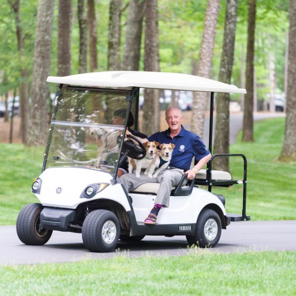 Couple in a golf car with three dogs