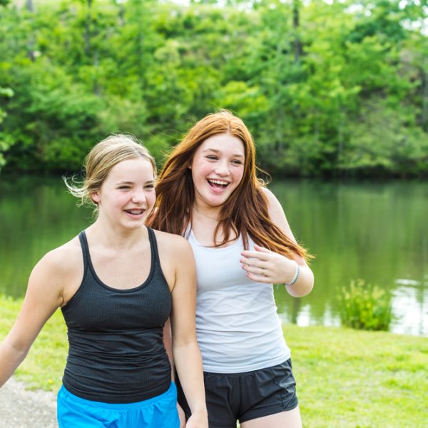 Two girls laughing in front of a lake.