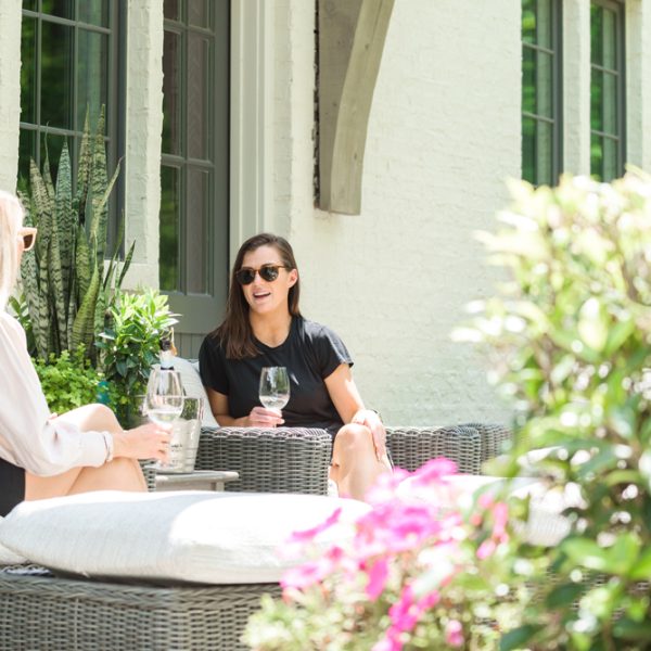 Two women talking and drinking wine wearing sunglasses