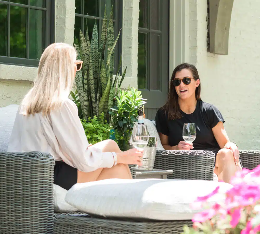 Two women talking and drinking wine wearing sunglasses
