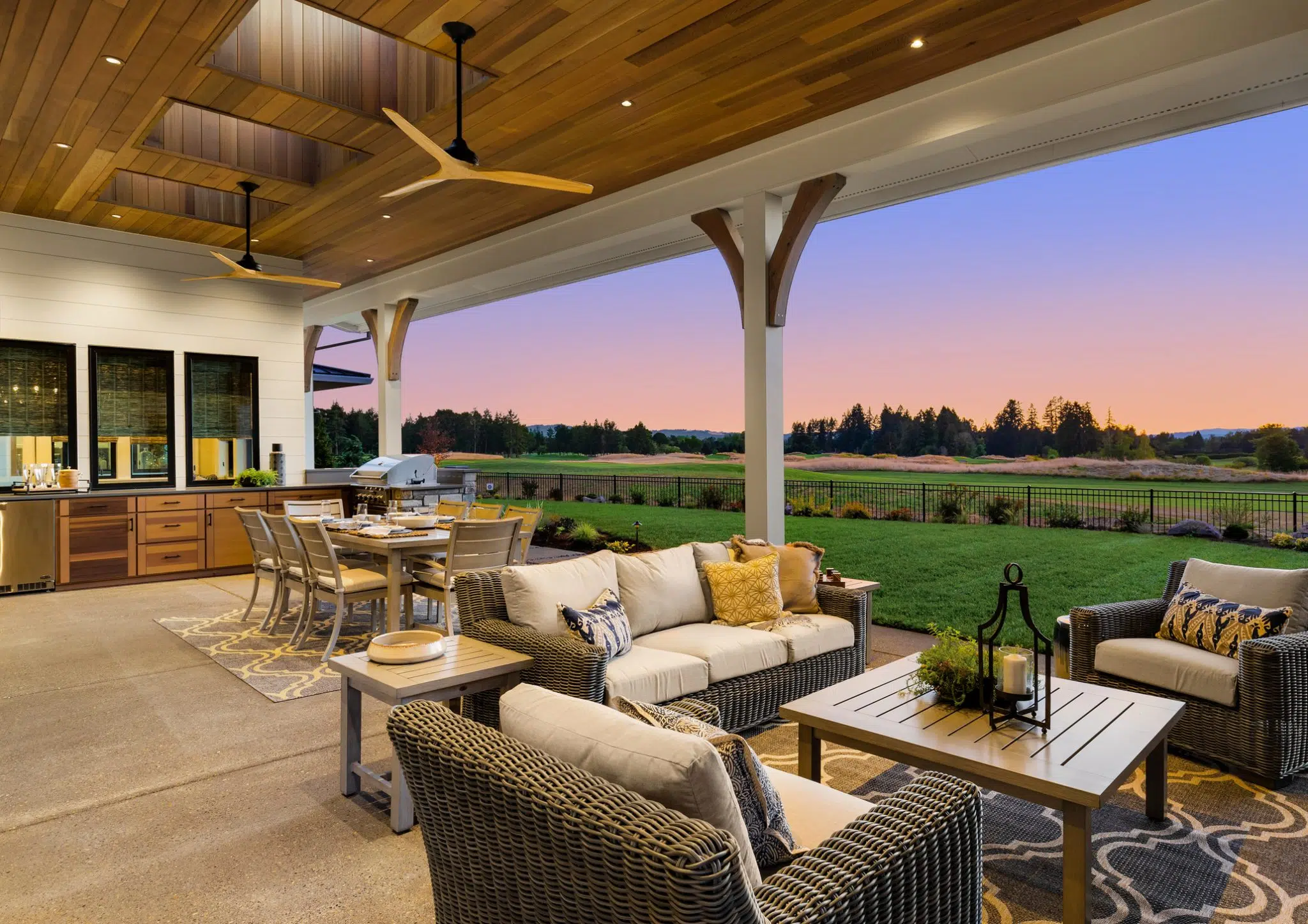 Luxury outdoor kitchen at sunset featuring a beautiful seating area, view of green spaces, and cooking amenities.