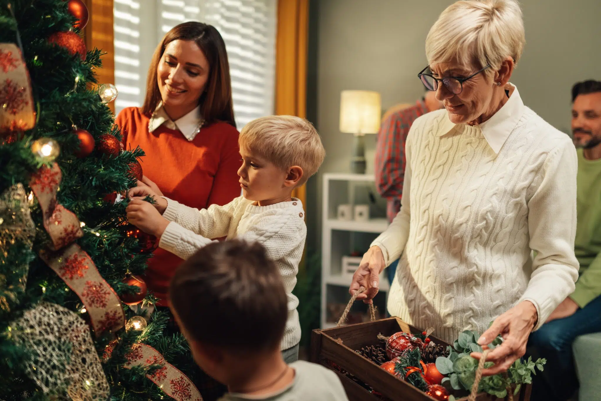 A family using holiday safety tips to decorate a Christmas tree together.