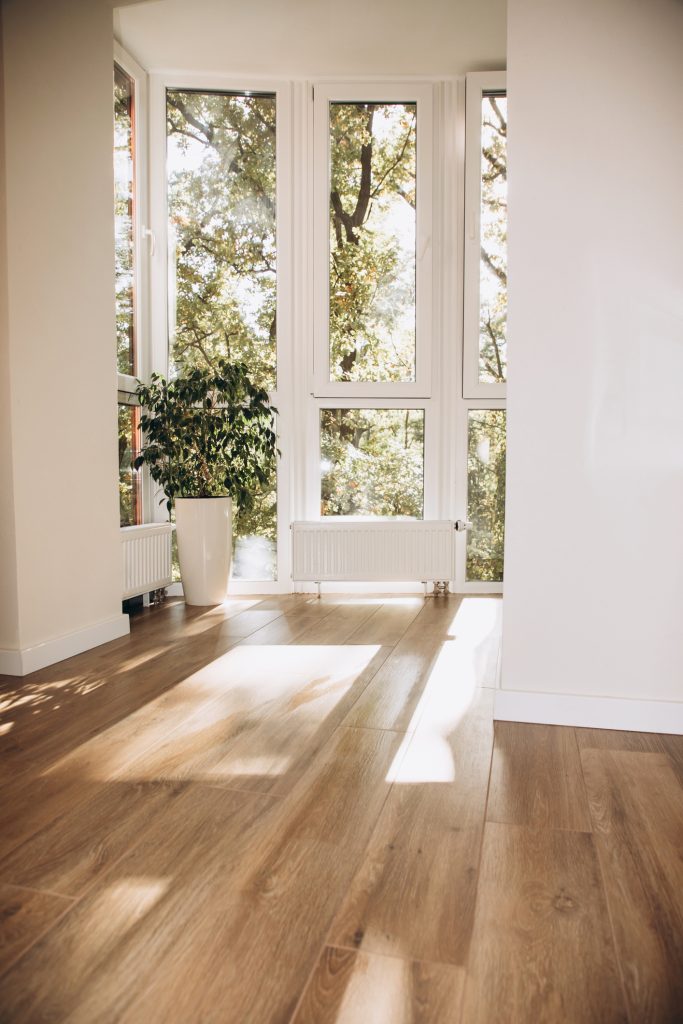 A view into a narrow room with high ceilings and plenty of windows that let in natural light, with a view of greenery.