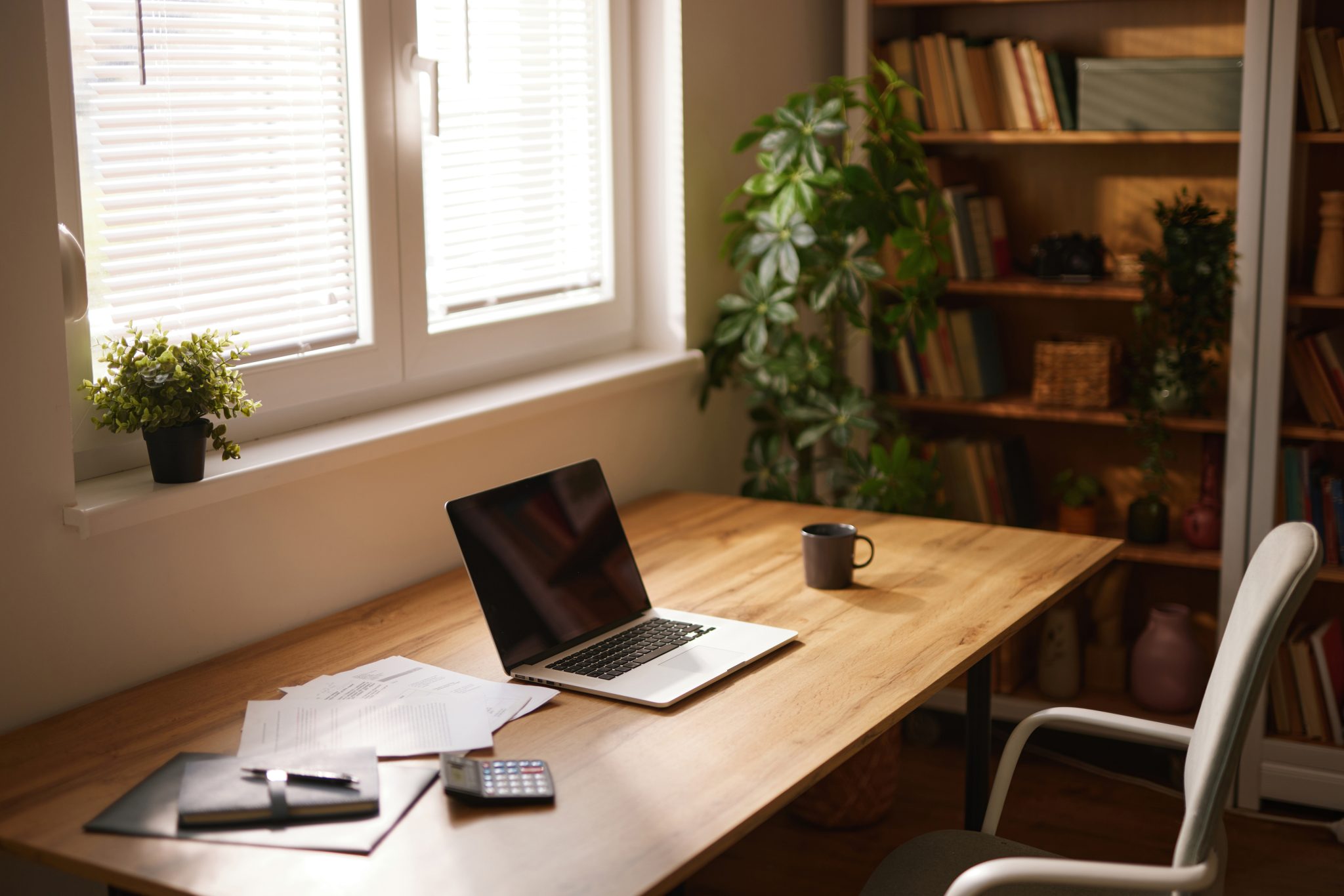 A simple home office featuring a desk, laptop, and shelves. Workspace optimization could improve productivity here.