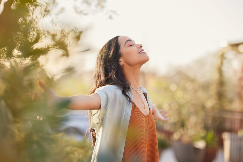 Woman enjoying a peaceful sunset with arms outstretched, reflecting the calm of quiet neighborhood living