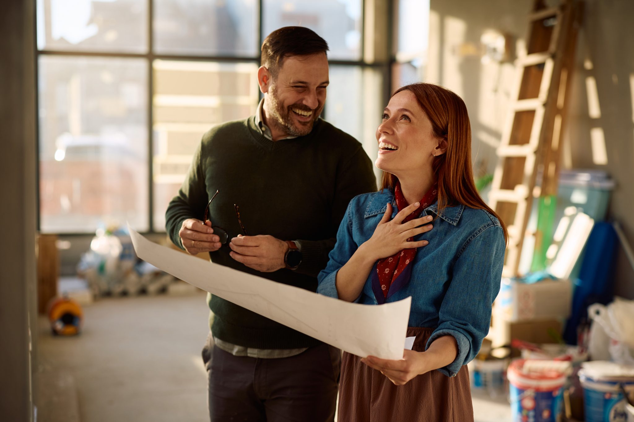 Smiling couple painting and renovating their home together while deciding between a remodel or a move